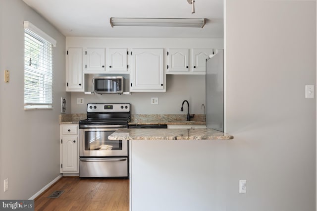 1100 Clarke St, Herndon, VA 20170 - kitchen with stainless steel appliances, light wood finished floors, white cabinetry, baseboards, and light stone counters