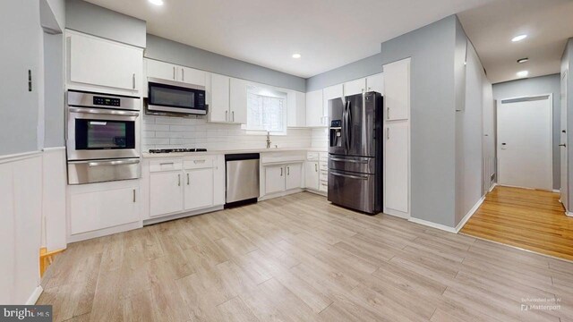 35 Bayberry Rd, Ewing, NJ 08618 - kitchen featuring stainless steel appliances, a warming drawer, light wood-style flooring, white cabinets, and a wainscoted wall