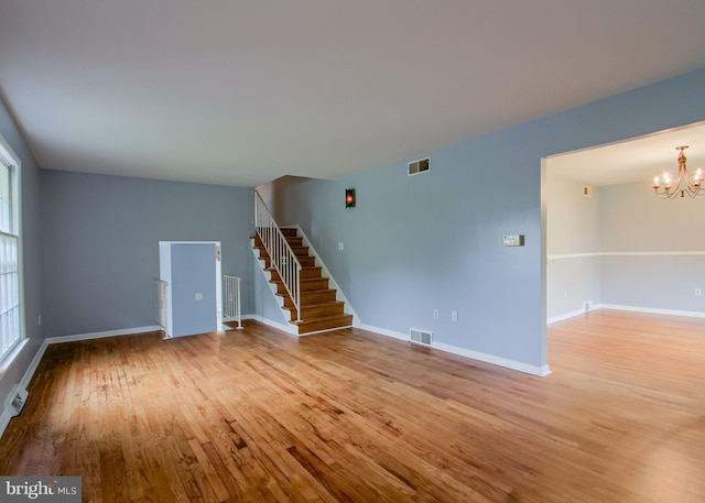 3900 Mark Ave, Harrisburg, PA 17110 - unfurnished living room with wood finished floors, stairs, a chandelier, and baseboards