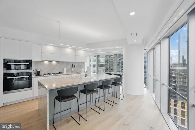 1111 19th St N Unit 2108, Arlington, VA 22209 - kitchen with modern cabinets, white cabinetry, a breakfast bar, white gas stovetop, and backsplash