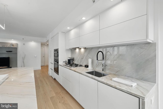 1111 19th St N Unit 2108, Arlington, VA 22209 - kitchen featuring a sink, modern cabinets, white cabinets, light stone counters, and stainless steel gas cooktop
