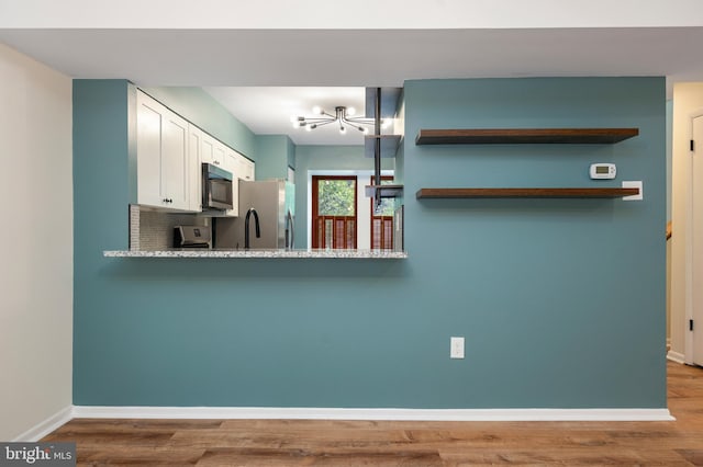 9441 Clocktower Ln, Columbia, MD 21046 - kitchen with appliances with stainless steel finishes, baseboards, white cabinetry, a chandelier, and wood finished floors
