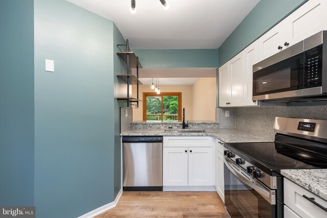 9441 Clocktower Ln, Columbia, MD 21046 - kitchen featuring stainless steel appliances, a sink, light wood-type flooring, tasteful backsplash, and white cabinets