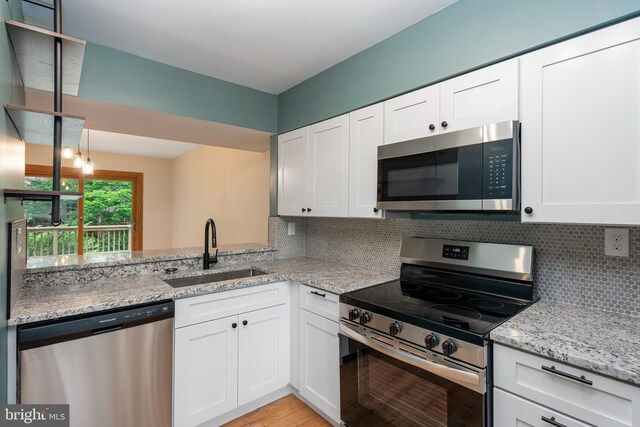 9441 Clocktower Ln, Columbia, MD 21046 - kitchen with appliances with stainless steel finishes, a sink, light stone countertops, white cabinetry, and tasteful backsplash