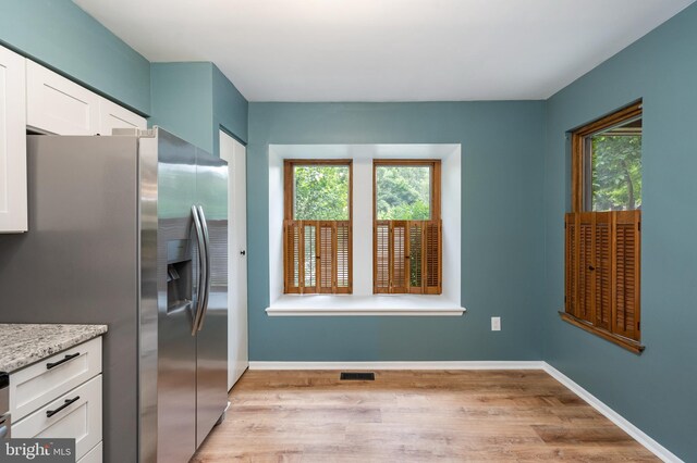 9441 Clocktower Ln, Columbia, MD 21046 - kitchen featuring stainless steel fridge with ice dispenser, light wood-style floors, white cabinets, baseboards, and light stone counters