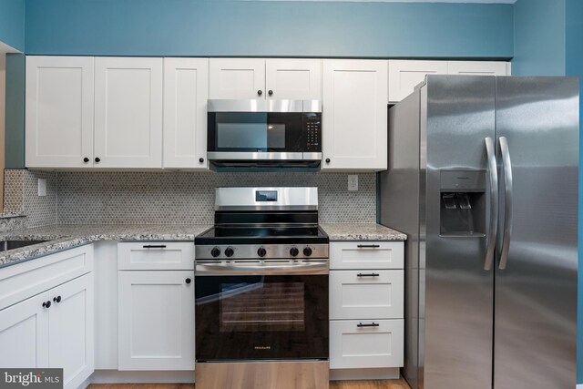 9441 Clocktower Ln, Columbia, MD 21046 - kitchen with appliances with stainless steel finishes, white cabinetry, light stone counters, and backsplash
