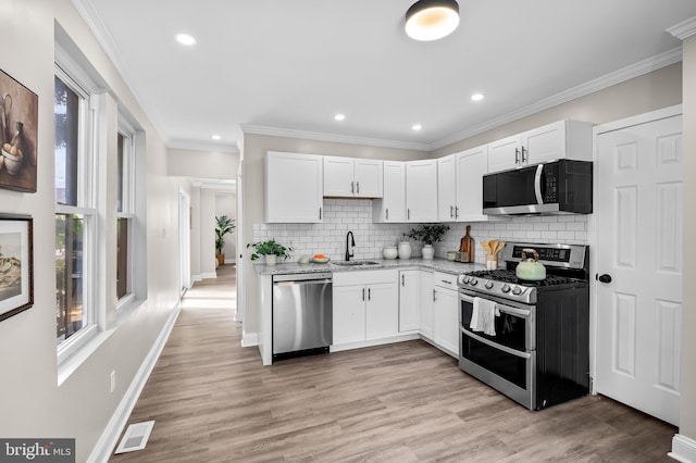 1402 W Old Cold Spring Ln, Baltimore, MD 21209 - kitchen featuring appliances with stainless steel finishes, a sink, white cabinets, tasteful backsplash, and baseboards