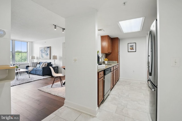 11800 Sunset Hills Rd Unit 717, Reston, VA 20190 - kitchen featuring appliances with stainless steel finishes, brown cabinets, open floor plan, baseboards, and light stone countertops