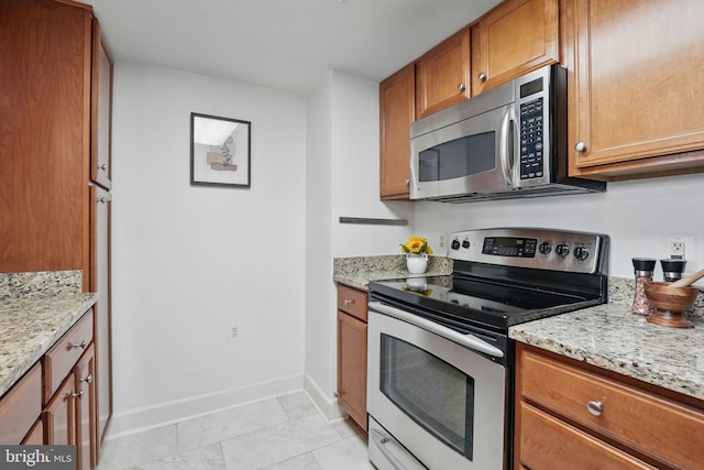 11800 Sunset Hills Rd Unit 717, Reston, VA 20190 - kitchen with stainless steel appliances, baseboards, light stone countertops, and brown cabinets
