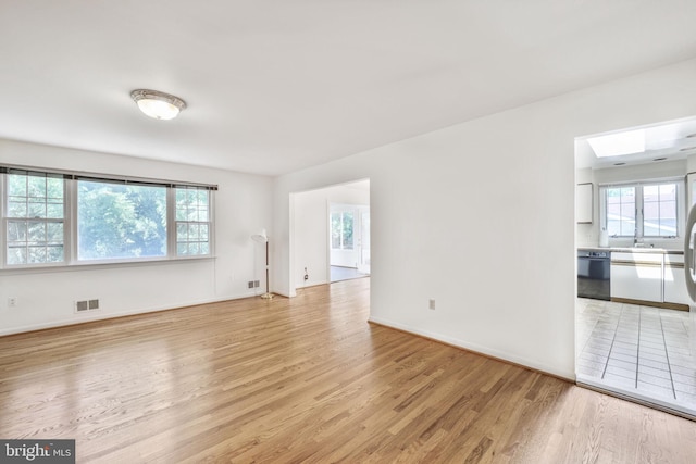 12403 Sir Lancelot Dr, Glenn Dale, MD 20769 - empty room with light wood-style flooring, a skylight, baseboards, and a sink