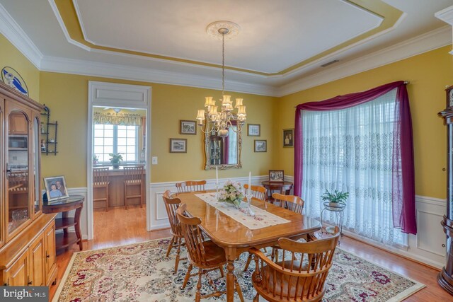 29865 Hillary Ave, Easton, MD 21601 - dining area with a chandelier, a tray ceiling, wainscoting, light wood finished floors, and crown molding