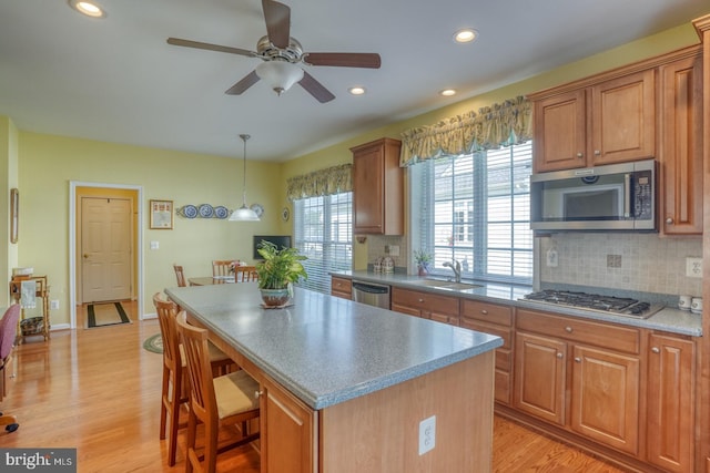 29865 Hillary Ave, Easton, MD 21601 - kitchen with appliances with stainless steel finishes, a center island, decorative backsplash, a ceiling fan, and light wood-style floors