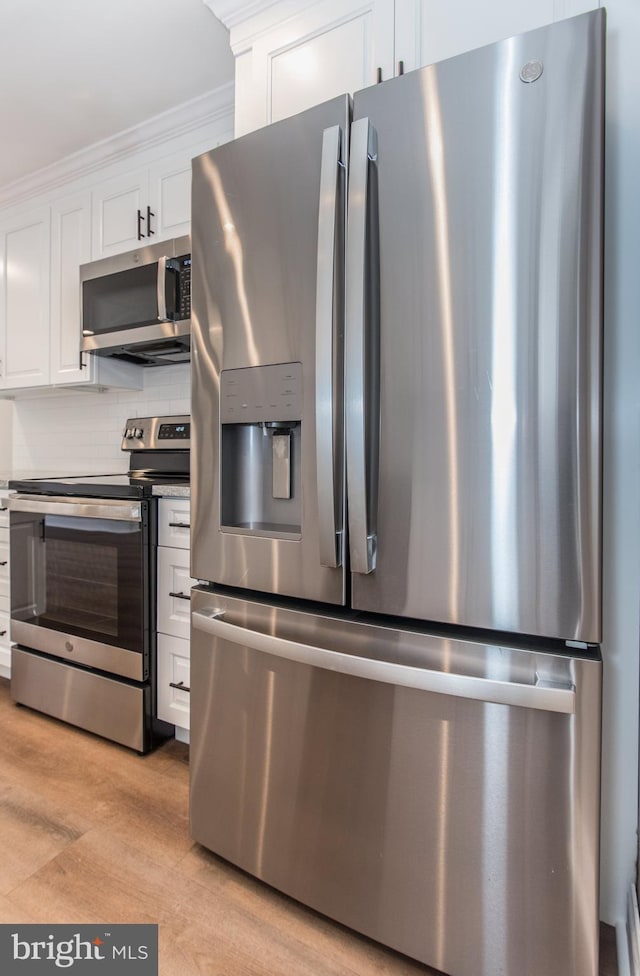 351 Doone Rd, Fairless Hills, PA 19030 - kitchen featuring appliances with stainless steel finishes, white cabinets, backsplash, light wood-type flooring, and crown molding