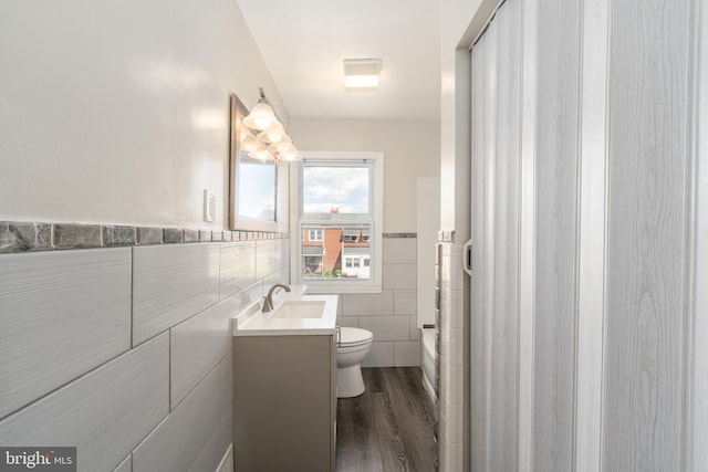 1738 Stokesley Rd, Baltimore, MD 21222 - bathroom featuring tile walls, vanity, toilet, wood finished floors, and a wainscoted wall