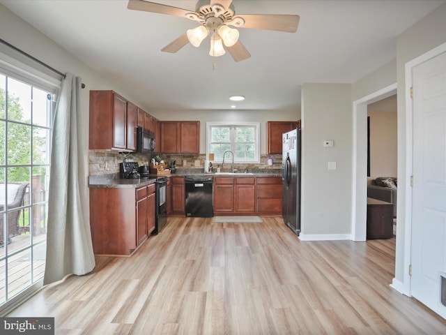 112 Toulouse Ln, Martinsburg, WV 25403 - kitchen featuring black appliances, a sink, light wood finished floors, decorative backsplash, and dark countertops