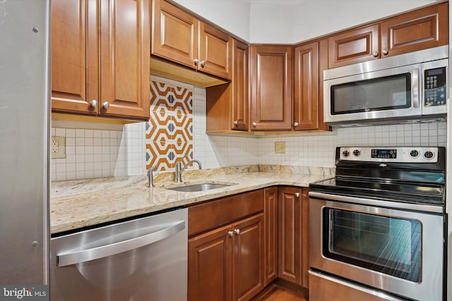 413 Eagle Rd # 7, Wayne, PA 19087 - kitchen with appliances with stainless steel finishes, light stone countertops, a sink, backsplash, and brown cabinetry