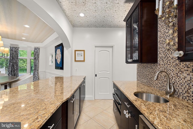 777 3rd St, Herndon, VA 20170 - kitchen with a sink, backsplash, light stone countertops, arched walkways, and light tile patterned flooring