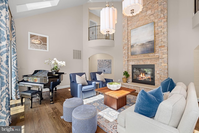 777 3rd St, Herndon, VA 20170 - living room with wood-type flooring, a stone fireplace, high vaulted ceiling, baseboards, and a skylight