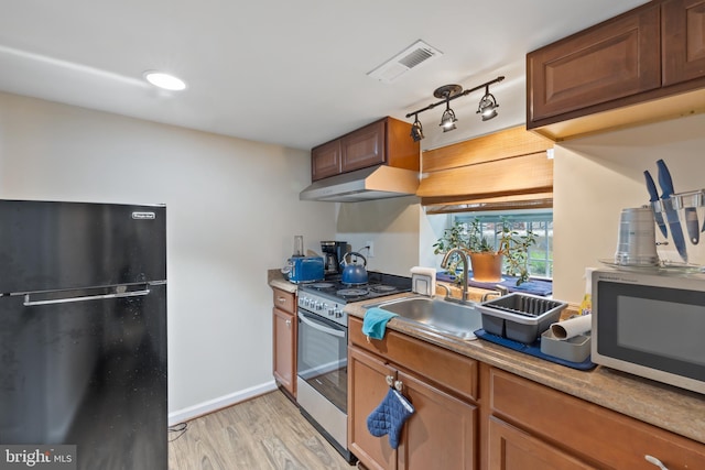 4909 Meade St NE, Washington, DC 20019 - kitchen featuring freestanding refrigerator, under cabinet range hood, stainless steel electric range oven, light wood finished floors, and a sink