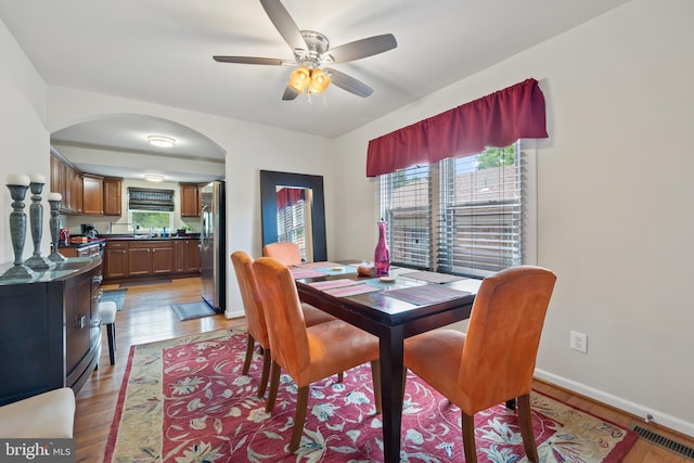4909 Meade St NE, Washington, DC 20019 - dining space featuring arched walkways, ceiling fan, light wood-style flooring, and baseboards