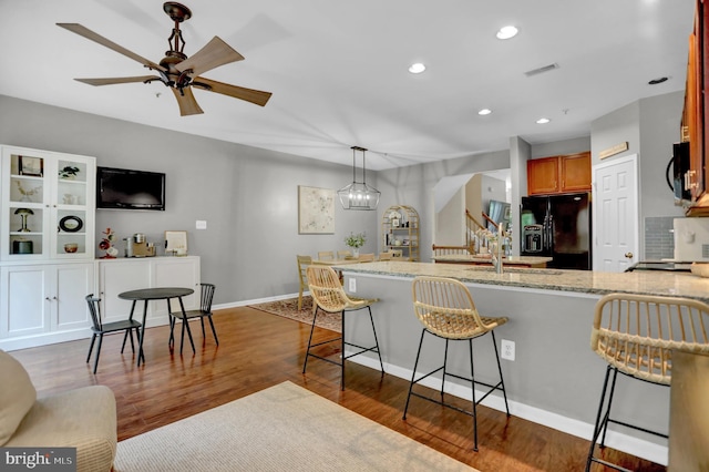 3061 Raking Leaf Dr, Abingdon, MD 21009 - kitchen with black appliances, a kitchen breakfast bar, light stone counters, dark wood-style flooring, and recessed lighting