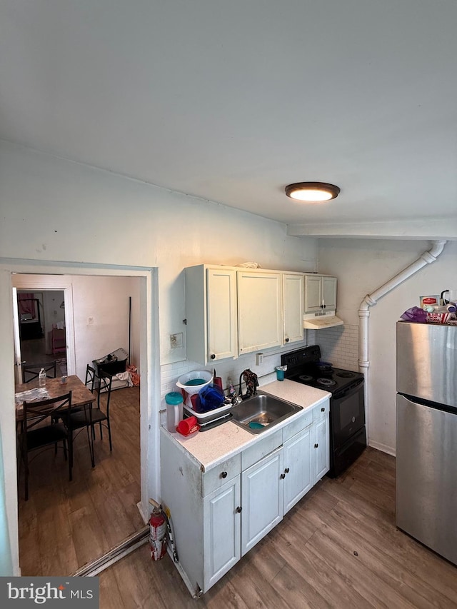 2338 W Hagert St, Philadelphia, PA 19132 - kitchen with freestanding refrigerator, electric range, a sink, wood finished floors, and light countertops