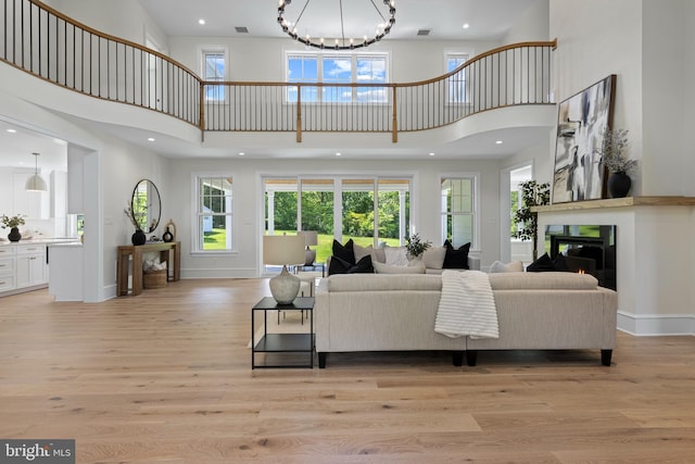 3718 Gradyville Rd, Newtown Square, PA 19073 - living room featuring a towering ceiling, a glass covered fireplace, light wood-style flooring, a chandelier, and baseboards
