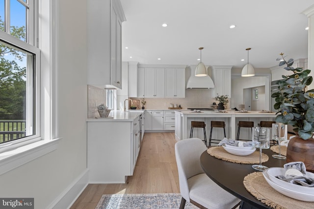 3718 Gradyville Rd, Newtown Square, PA 19073 - kitchen featuring custom range hood, tasteful backsplash, light countertops, white cabinetry, and light wood-type flooring