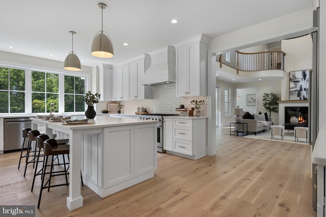 3718 Gradyville Rd, Newtown Square, PA 19073 - kitchen with custom range hood, appliances with stainless steel finishes, decorative backsplash, white cabinets, and light countertops