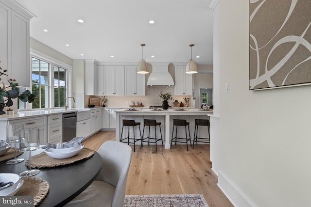 3718 Gradyville Rd, Newtown Square, PA 19073 - kitchen featuring premium range hood, dishwashing machine, a kitchen breakfast bar, backsplash, and white cabinetry