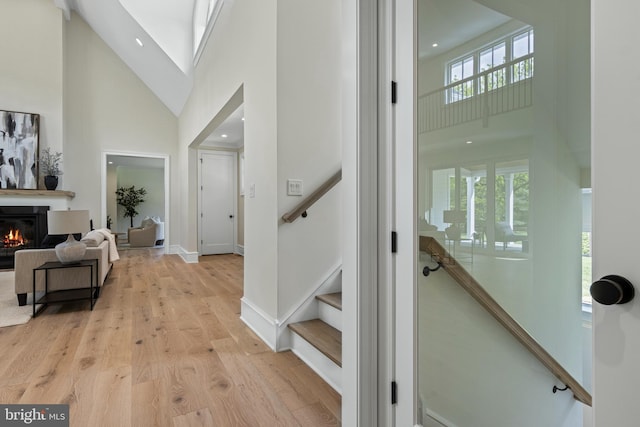 3718 Gradyville Rd, Newtown Square, PA 19073 - entrance foyer featuring high vaulted ceiling, light wood-style flooring, stairway, a glass covered fireplace, and baseboards