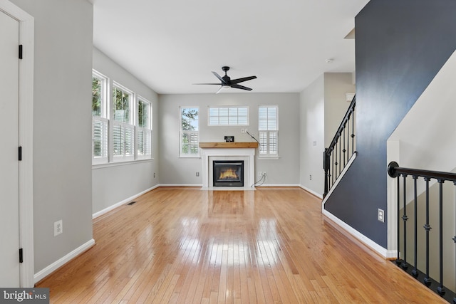 9901 Airedale Ct, Bristow, VA 20136 - unfurnished living room featuring a ceiling fan, light wood-style floors, a fireplace with flush hearth, baseboards, and stairway