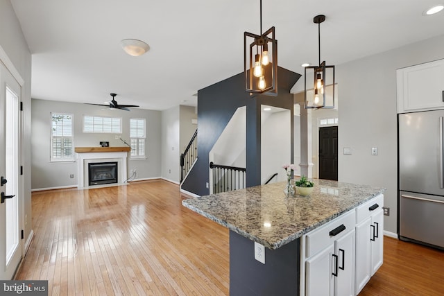 9901 Airedale Ct, Bristow, VA 20136 - kitchen featuring stainless steel fridge, ceiling fan, light wood-type flooring, and a glass covered fireplace