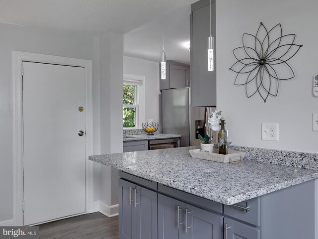 6202 K St, Capitol Heights, MD 20743 - kitchen with dark wood-style flooring, baseboards, light stone countertops, a peninsula, and pendant lighting