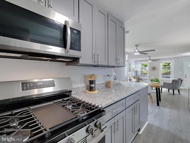 6202 K St, Capitol Heights, MD 20743 - kitchen with stainless steel appliances, gray cabinets, light wood-style floors, a ceiling fan, and light stone countertops