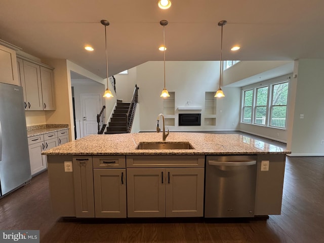 2410 Vineyard Springs Way, Ellicott City, MD 21043 - kitchen featuring appliances with stainless steel finishes, a sink, open floor plan, light stone countertops, and a fireplace