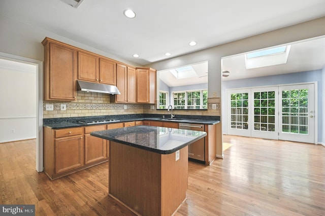 10861 Hunter Gate Way, Reston, VA 20194 - kitchen with a skylight, appliances with stainless steel finishes, under cabinet range hood, a kitchen island, and light wood finished floors