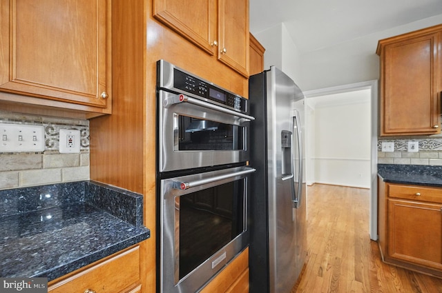 10861 Hunter Gate Way, Reston, VA 20194 - kitchen featuring stainless steel appliances, brown cabinets, light wood-type flooring, tasteful backsplash, and dark stone counters