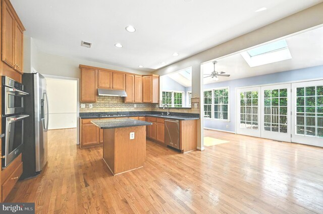 10861 Hunter Gate Way, Reston, VA 20194 - kitchen featuring stainless steel appliances, a skylight, a kitchen island, under cabinet range hood, and backsplash