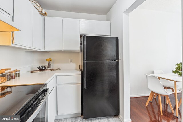 2630 Adams Mill Rd NW Unit 302, Washington, DC 20009 - kitchen with freestanding refrigerator, light countertops, light wood-style floors, and white cabinetry