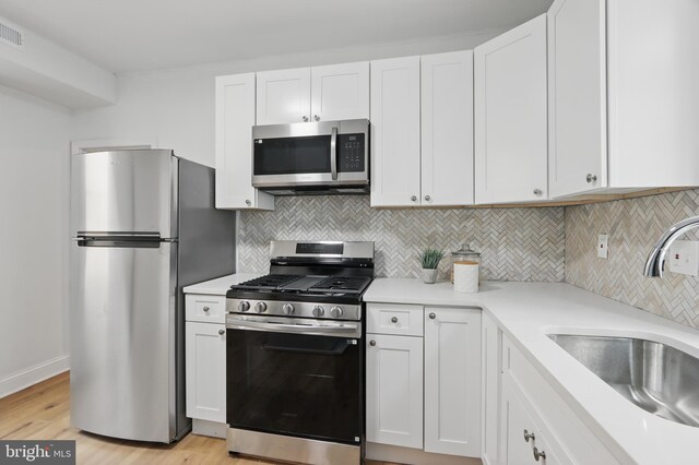 405 Calvin Ave, Baltimore, MD 21218 - kitchen featuring appliances with stainless steel finishes, a sink, light wood-style flooring, and white cabinetry