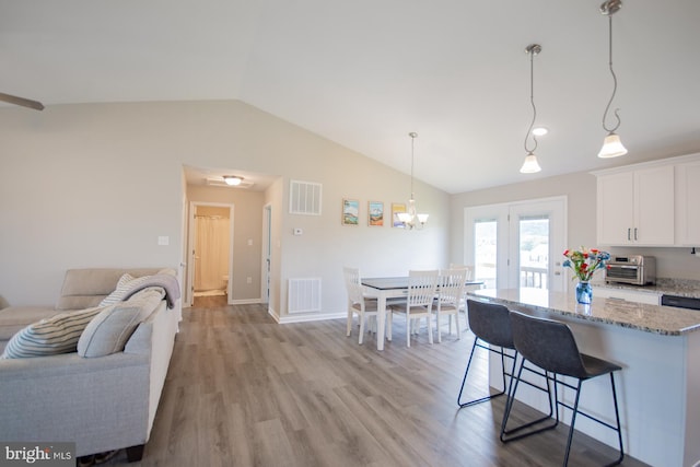 316 Pochards Ct, Martinsburg, WV 25403 - kitchen with lofted ceiling, light stone countertops, light wood-style flooring, white cabinetry, and a kitchen breakfast bar