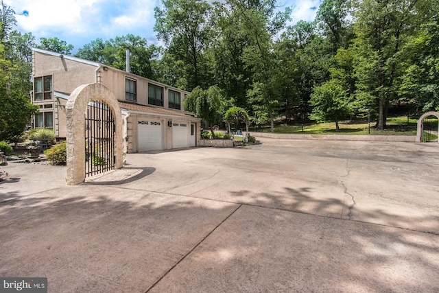 2500 Edge Hill Rd, Huntingdon Valley, PA 19006 - view of side of home featuring concrete driveway, an attached garage, stucco siding, and view of scattered trees