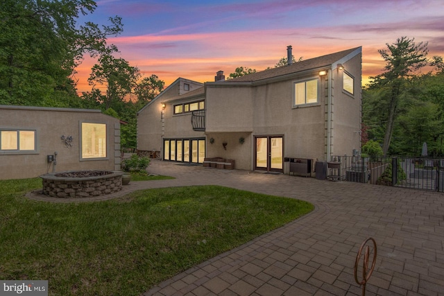 2500 Edge Hill Rd, Huntingdon Valley, PA 19006 - back of house at dusk with a patio, an outdoor fire pit, french doors, stucco siding, and a balcony