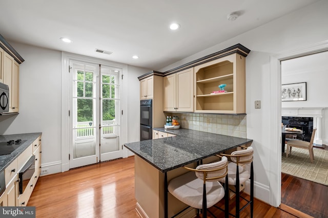 3 Devon Hill Rd Unit D4, Baltimore, MD 21210 - kitchen with a warming drawer, light wood-style floors, tasteful backsplash, a kitchen breakfast bar, and cream cabinetry