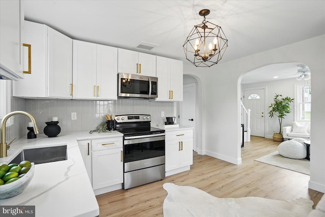 12 N Hawthorne Rd N, Middle River, MD 21220 - kitchen with appliances with stainless steel finishes, a sink, arched walkways, light wood finished floors, and backsplash