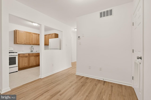 7056 Eastern NW Unit 308, Washington, DC 20012 - kitchen featuring white appliances, light countertops, light wood-style flooring, a sink, and baseboards