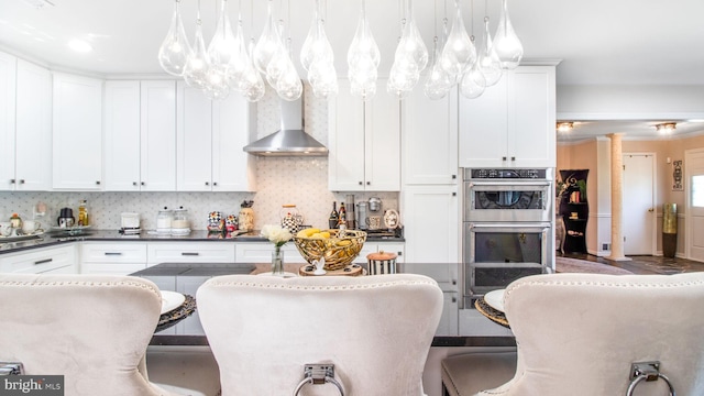 11500 Golden Post Ln, Gaithersburg, MD 20878 - kitchen featuring double oven, dark countertops, wall chimney range hood, white cabinets, and decorative backsplash