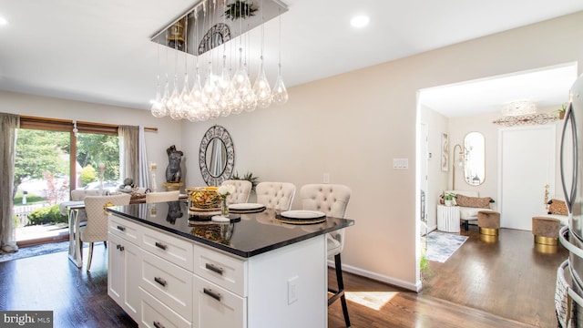 11500 Golden Post Ln, Gaithersburg, MD 20878 - kitchen with a kitchen bar, dark wood-style floors, white cabinets, dark countertops, and a center island