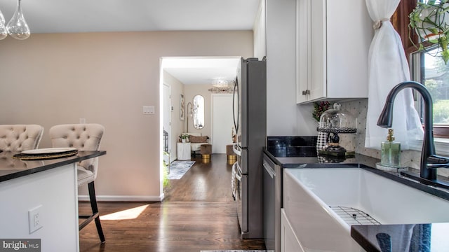 11500 Golden Post Ln, Gaithersburg, MD 20878 - kitchen with a sink, dark countertops, a chandelier, white cabinetry, and a kitchen breakfast bar